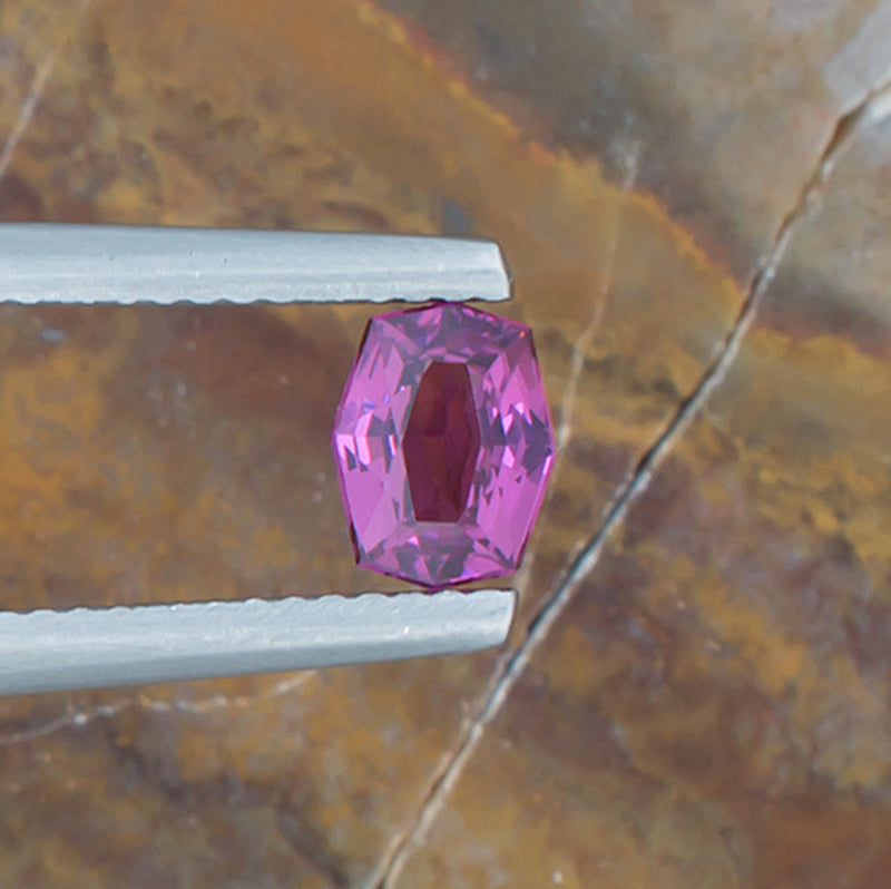 0.83ct Rhodolite Garnet Colored Gemstone Top View Natural Background 
