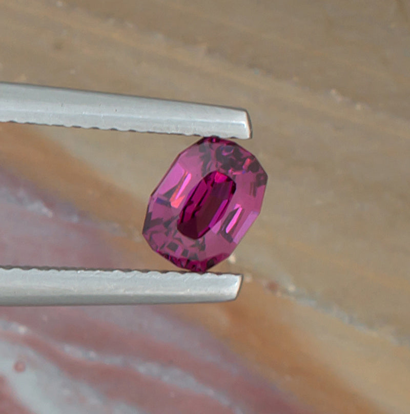 0.88ct Rhodolite Garnet Colored Gemstone Top View Angle Natural Background 