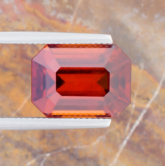 12.02ct Hessonite Garnet Colored Gemstone Top View Tweezers Natural Background